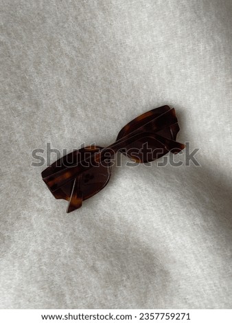 Brown sunglasses laying on a cream color wool blanket. Close-up picture of details, luxurious sunnies, accessories in clothing, no people, autumn style, winter fashion, neutral tones, minimalistic
