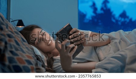 Indian upset sad alone woman crying lying on bed using mobile phone chatting late night at indoor home. Lonely unhappy female looking on smartphone screen typing reading bad massage at inside house Royalty-Free Stock Photo #2357765853