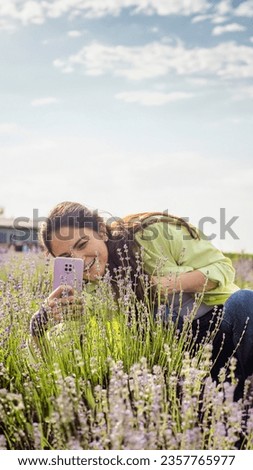 happy smiling woman takes a picture of blooming lavender on her phone. Flower psychotherapy. Walk to the blooming lavender field. Fight stress. Phototherapy - type of art therapy. healthy mind