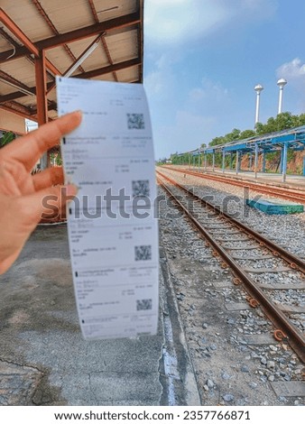 In this picture, one hand holds a train ticket.  which symbolizes the upcoming journey.  Behind the tracks stretched out to the horizon.  This element captures the excitement of travel and adventure.