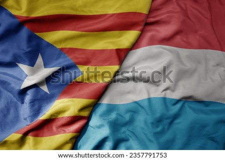 big waving national colorful flag of catalonia and national flag of luxembourg . macro