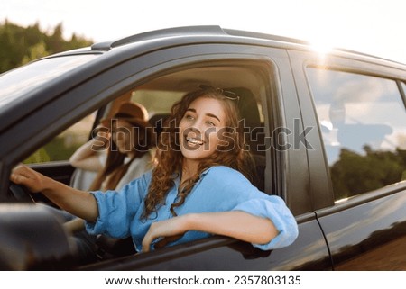 Two women travelers travel by car, have fun. Beautiful female friends in the car enjoy a car trip together. Travel, tourism. Royalty-Free Stock Photo #2357803135