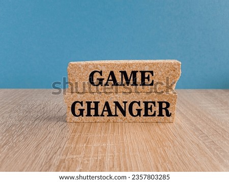 Brick blocks with words Game changer. Beautiful wooden table, blue background, copy space. Game changer business or political change concept and disruptive innovation.