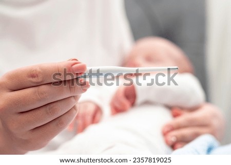 Checking infant temperature in loving arms, Concept of health precautions for newborns Royalty-Free Stock Photo #2357819025