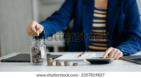 saving money with hand putting coins in jug glass and calculator to calculate budget concept finance and accounting and Gantt chart diagram. in office Royalty-Free Stock Photo #2357819827
