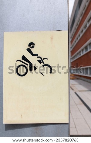 Worn and colorless motorcycle driving traffic sign with a flat background on one side and a hallway to give it depth on the other