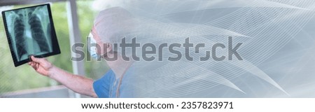 Surgeon wearing a medical face mask and examining lungs x-ray during coronavirus outbreak; panoramic banner