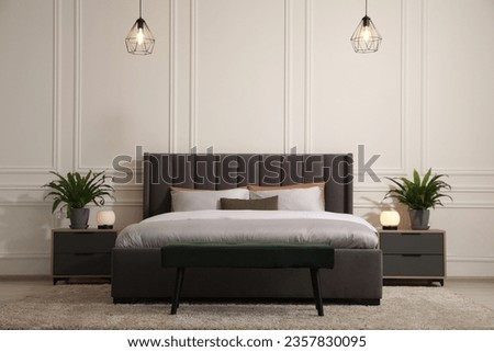 Stylish bedroom interior with large comfortable bed and ottoman Royalty-Free Stock Photo #2357830095