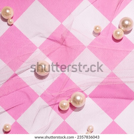 Pastel pink tulle and beads scattered on the background of a checkered pattern, retro nostalgia.