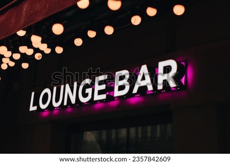 Neon sign on a black background, the inscription Lounge bar with pink light