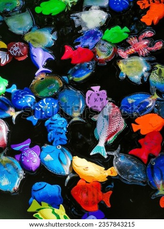 A lot of children's toy colorful plastic and rubber fish on the surface of the water.