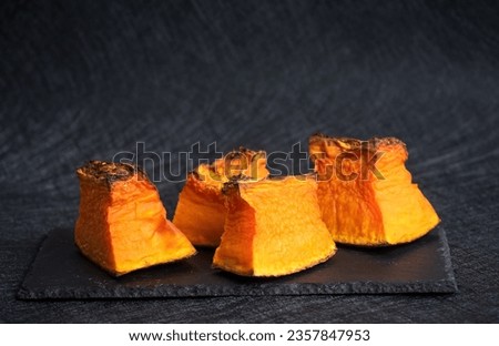 A few slices of roasted pumpkin on a black background