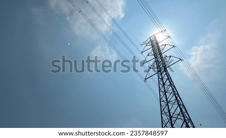 High voltage post. High voltage tower against cloudy blue sky and sun. high-voltage power lines at afternoon with hot sun, high voltage electric transmission tower