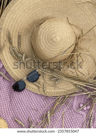 A straw hat on a knitted pink plaid, wheat ears, bread bagels and rolls in a wicker basket, sunglasses from the sun close-up view from above.