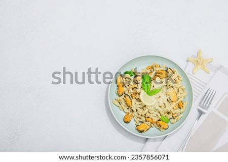Plant based pasta with mussels, pesto and parmesan cheese. Ready to eat healthy food, served portion on stone table. Hard light, dark shadow, flat lay, top view Royalty-Free Stock Photo #2357856071