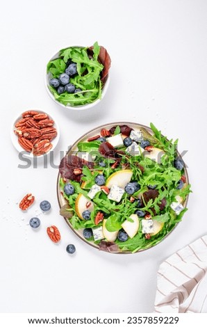 Salad with Pear, Arugula, Blue Cheese, Nuts and Blueberry, Delicious Fresh Salad on Bright Background Royalty-Free Stock Photo #2357859229