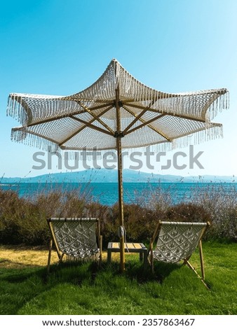 Two lounge chairs on grass with umbrella , Empty deck chairs with Seaascape environmental application concept. High quality photo Royalty-Free Stock Photo #2357863467
