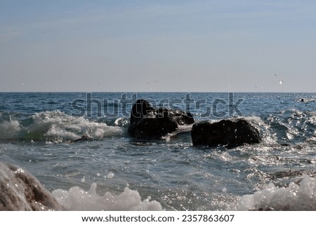 Sea wave splash on rocky beach. Ocean waves breaking on rocks. Sunny day nature background landscape photography.