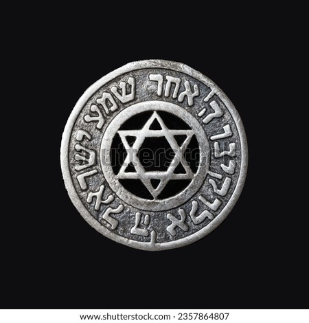 Old silver medallion with the Star of David and the text of the prayer "Hear, oh Israel, the Lord is our God, the Lord is one" on a black velvet background Royalty-Free Stock Photo #2357864807