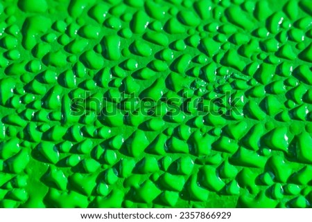 Water drops on green leaf in rays of sun, close-up macro. Raindrops on textured green metallic surface Royalty-Free Stock Photo #2357866929