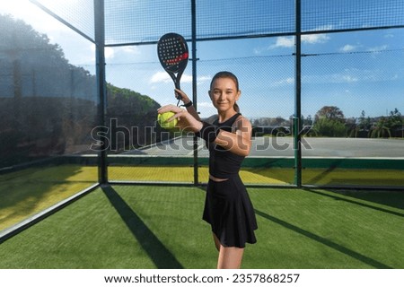 Padel tennis player with racket and ball in hands. Girl athlete with paddle racket on court outdoors. Sport concept. Download a high quality photo for the design of a sports app or web site.