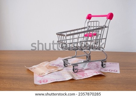 Shopping cart with Turkish banknotes on wooden table. Turkish lira on shopping trolley. Turkey finance, inflation and economic concept. Flat lay, copy space