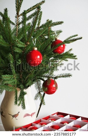 Fir branches in a vase with red Christmas balls on a white background