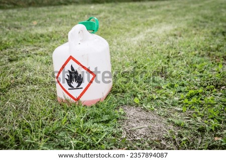 Fire danger sign. Plastic can in cut grass.