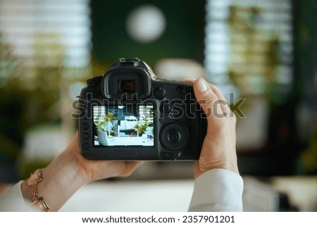Time to move on. Closeup on woman real estate agent in green office in white blouse with dslr photo camera making interior photo.