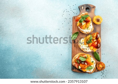 Toast, snack, bruschetta, sandwich with cream cheese, peaches, tomatoes and green basil leaves, Concept healthy and balanced eating. place for text, top view,