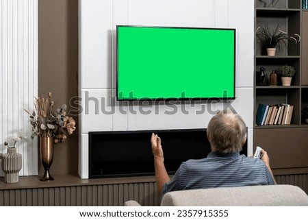 Aged man sitting on the couch and watching tv. Green screen concept