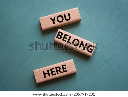 You belong here symbol. Wooden blocks with words You belong here. Beautiful grey green background. Business and You belong here concept. Copy space.