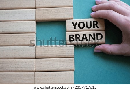 Your Brand symbol. Concept word Your Brand on wooden blocks. Businessman hand. Beautiful grey green background. Business and Your Brand concept. Copy space