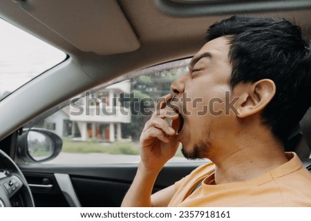 Asian man funny face yawning sleepy while driving a car.  Royalty-Free Stock Photo #2357918161