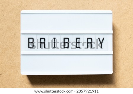 Lightbox with word bribery on wood background