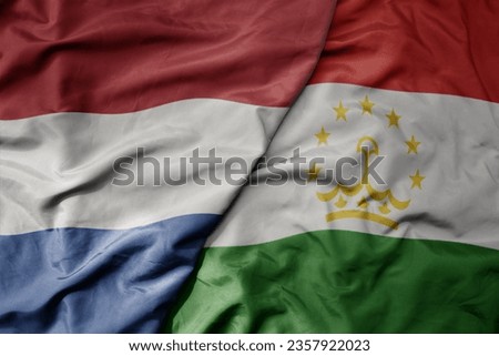 big waving national colorful flag of netherlands and national flag of tajikistan . macro