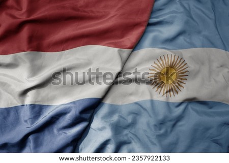 big waving national colorful flag of netherlands and national flag of argentina . macro