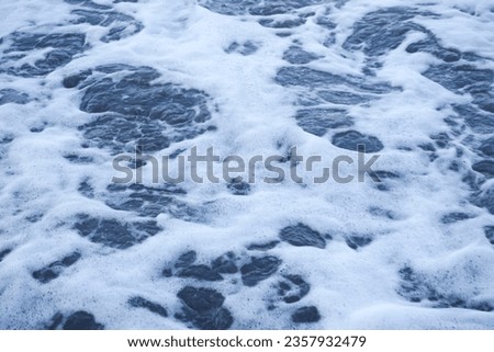 photo of foam foam resulting from waves crashing on the beach
