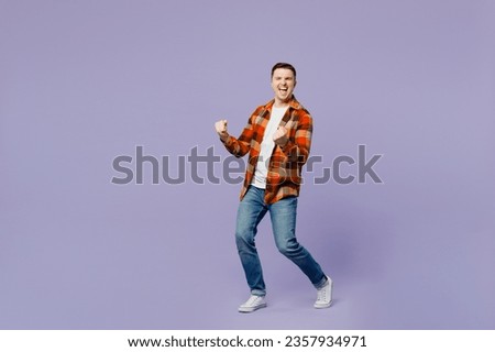 Full body side view young happy man he wears checkered shirt white t-shirt casual clothes doing winner gesture celebrate clenching fists say yes isolated on plain pastel light purple background studio