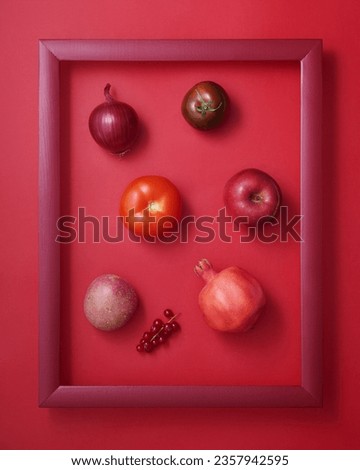 Onion, potato, tomatoes, pomegranate, apple and currant in wooden picture frame on red background