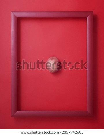 Whole red potato in wooden picture frame on red background