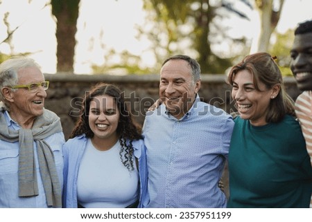 Group of multiracial people with different ages hugging each other outdoor with city park in background - Multi generational and community concept Royalty-Free Stock Photo #2357951199