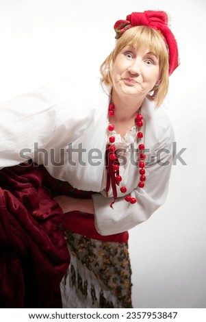 Portrait of heerful funny adult mature woman solokha washing clothes in a basin. Female model in national ethnic Slavic style. Stylized Ukrainian, Belarusian or Russian woman in comic photo shoot
