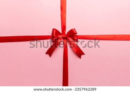 Top view of Red ribbon rolled and red bow isolated on colored background. Flat lay with copy space. Royalty-Free Stock Photo #2357962289