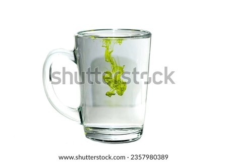 Green color of ink dropping in glass put on white background with isolated picture.