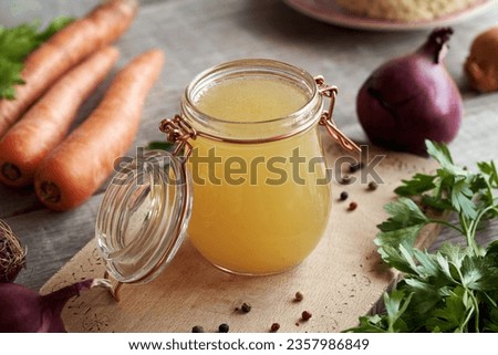 Chicken bone broth or soup in a glass jar with fresh vegetables