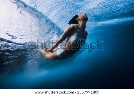 Surfgirl dive underwater under ocean wave. Duck dive under barrel wave in blue ocean Royalty-Free Stock Photo #2357991809