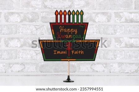 Happy Kwanzaa Day 7 (Imani - Faith) cake blackboard in front of white brick wall