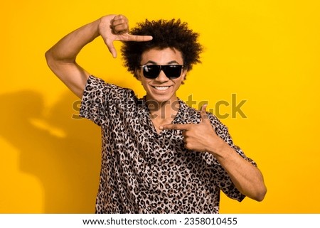 Photo of satisfied nice guy with afro hair dressed print shirt in sunglass hands focusing on smile isolated on yellow color background
