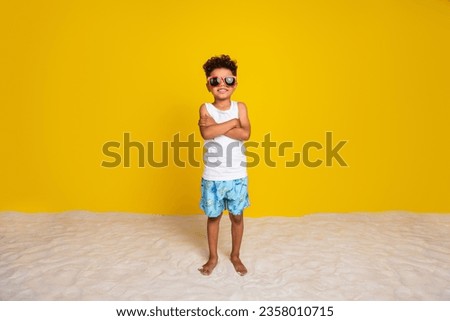 Full length photo of cool confident small boy wear white shirt dark eyewear arms crossed enjoying rest isolated yellow color background Royalty-Free Stock Photo #2358010715